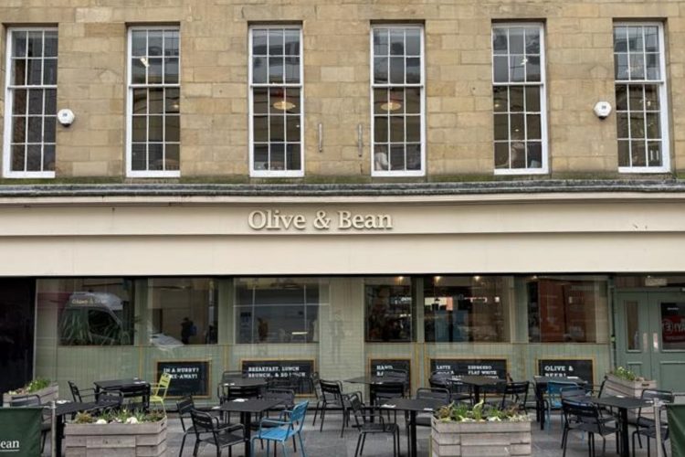 A photo of the Olive and Bean frontage in the Grainger Market Newcastle. Stone building with seating out the front