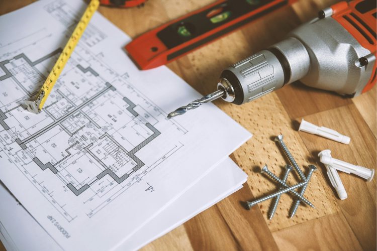 Drawing of a house plan with pencil and drill on top