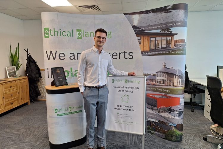 Thomas Grimshaw our Planner Standing in front of our exhibition stand and smiling