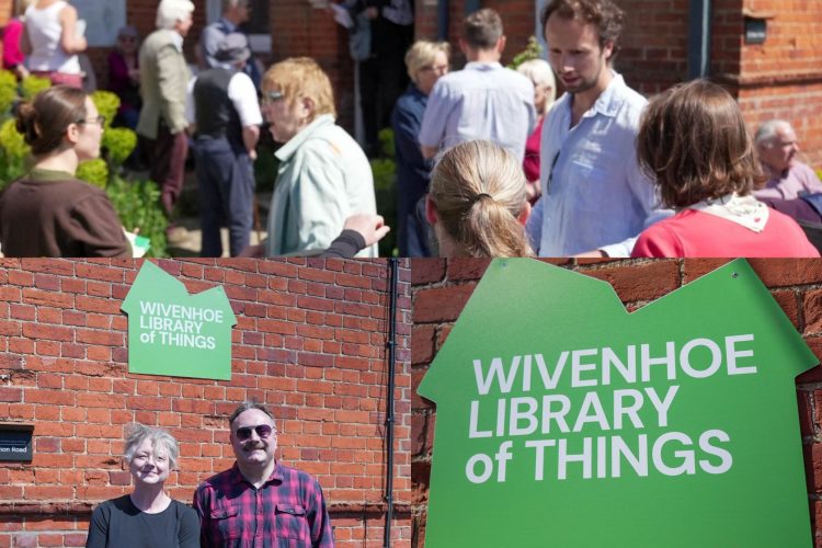 A picture of the Wivenhoe sign with 2 employees standing underneath